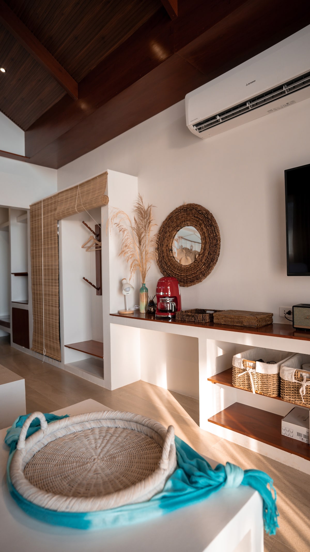 Villa interior detail with coffee maker, rattan mirror, TV, and storage