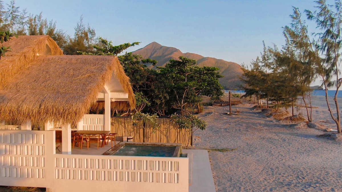 Aerial view of beachfront villa with pool and mountains
