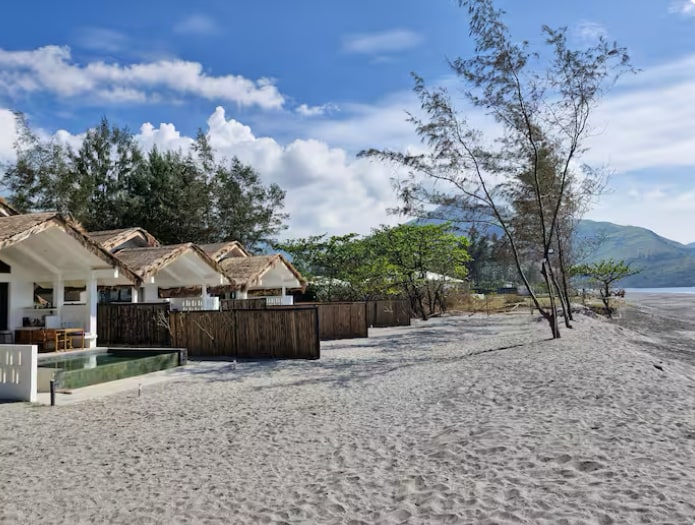 Beachfront villas from the sandy shore with mountains in the background