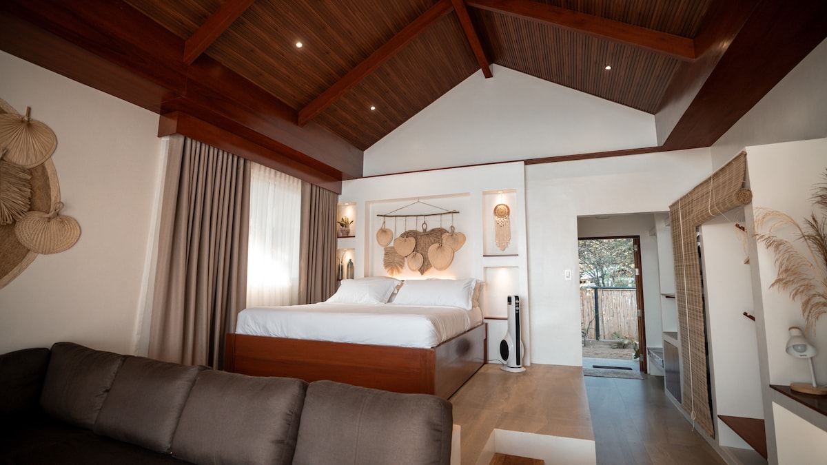 Villa bedroom with king-size bed, vaulted wooden ceiling, and boho decor